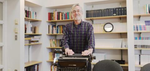 Professor Jack Lule stands behind a typewriter in the meeting room of Coppee Hall on Nov. 18.